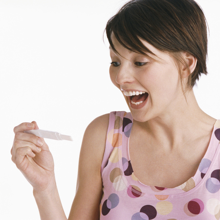 Happy woman holding pregnancy test